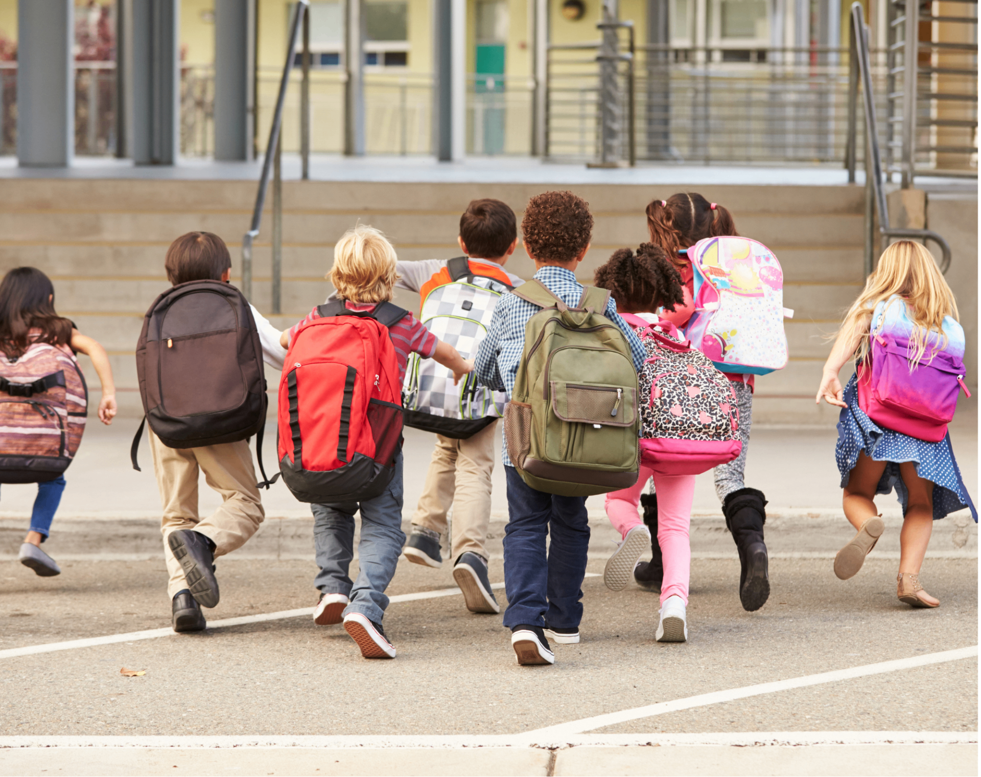 Elementary students with backpacks running into school